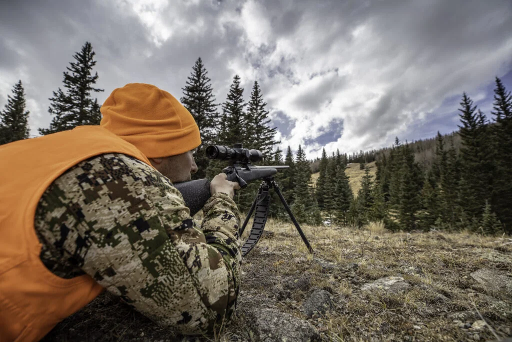 Hunter prone in backcountry terrain with rifle on a bipod