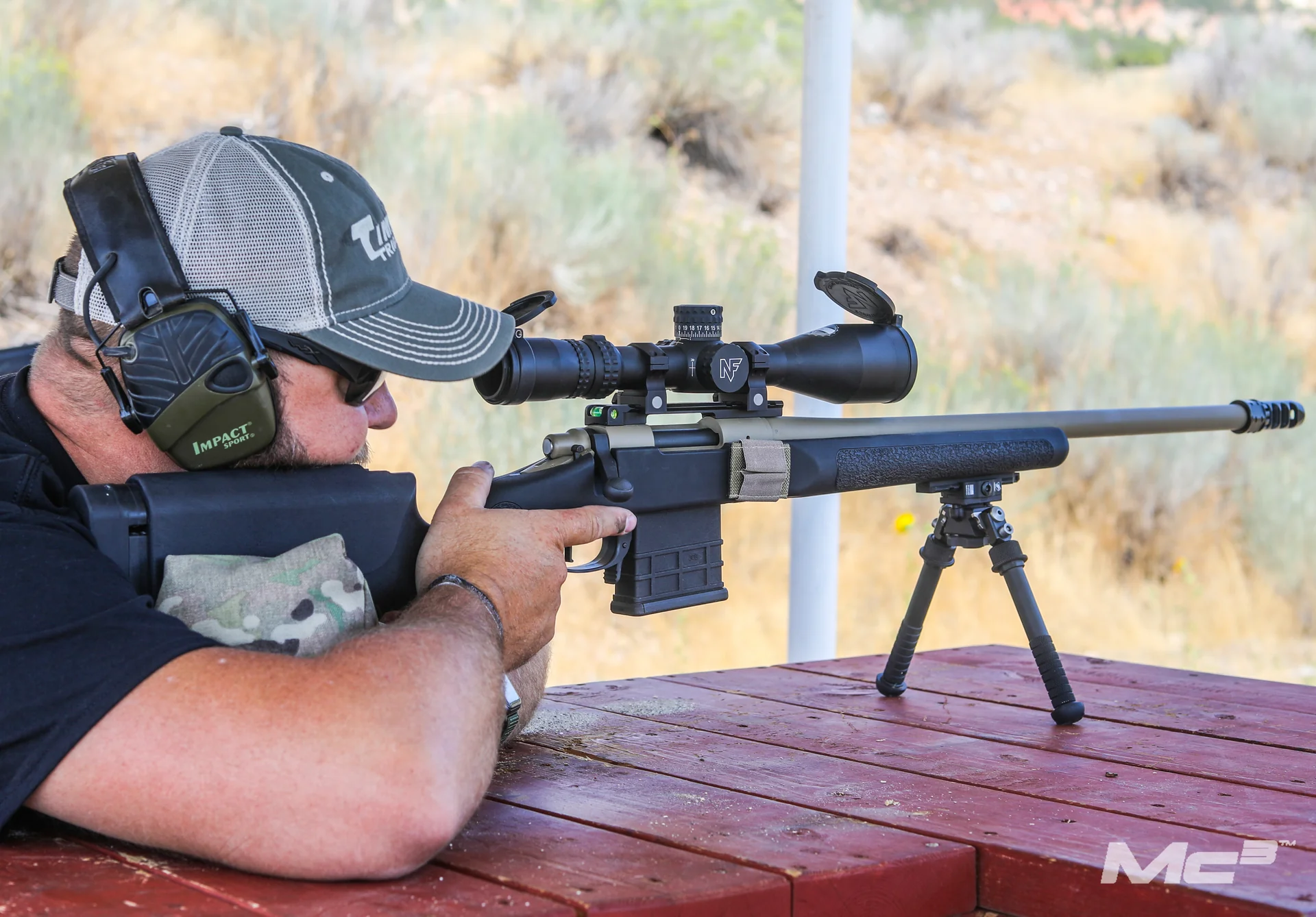 Atlas bipod deployed under a bolt-action rifle with Nightforce scope as a shooter aims from a range bench.