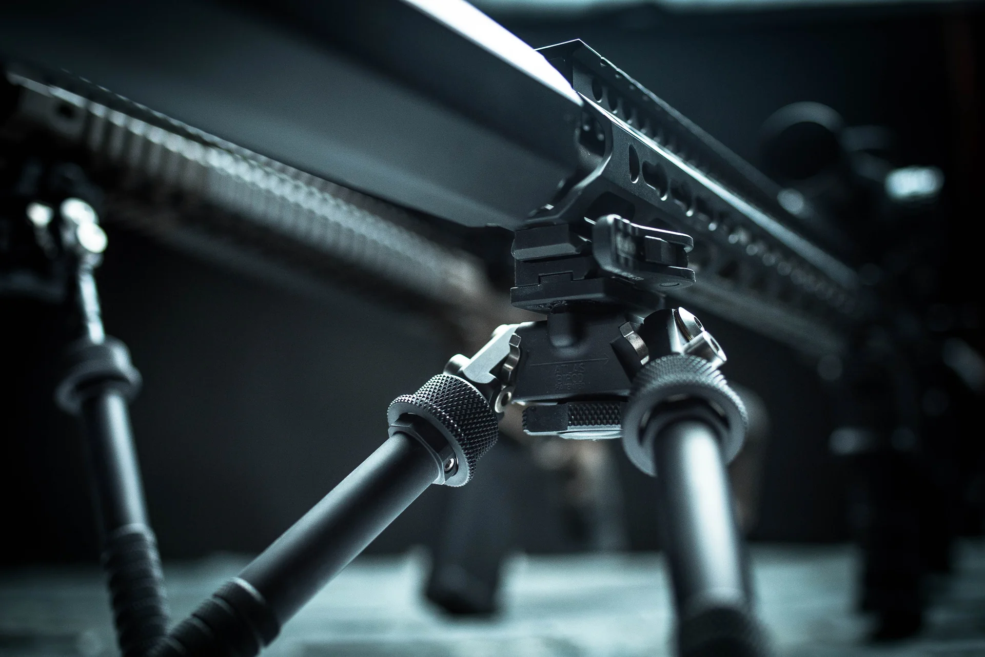 Atlas bipod deployed low-angle showing notched aluminum legs and cant body under a precision rifle rail.