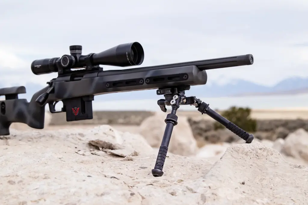 Atlas CAL BT65-LW17 bipod supporting a suppressed bolt-action rifle deployed on white rock in open country