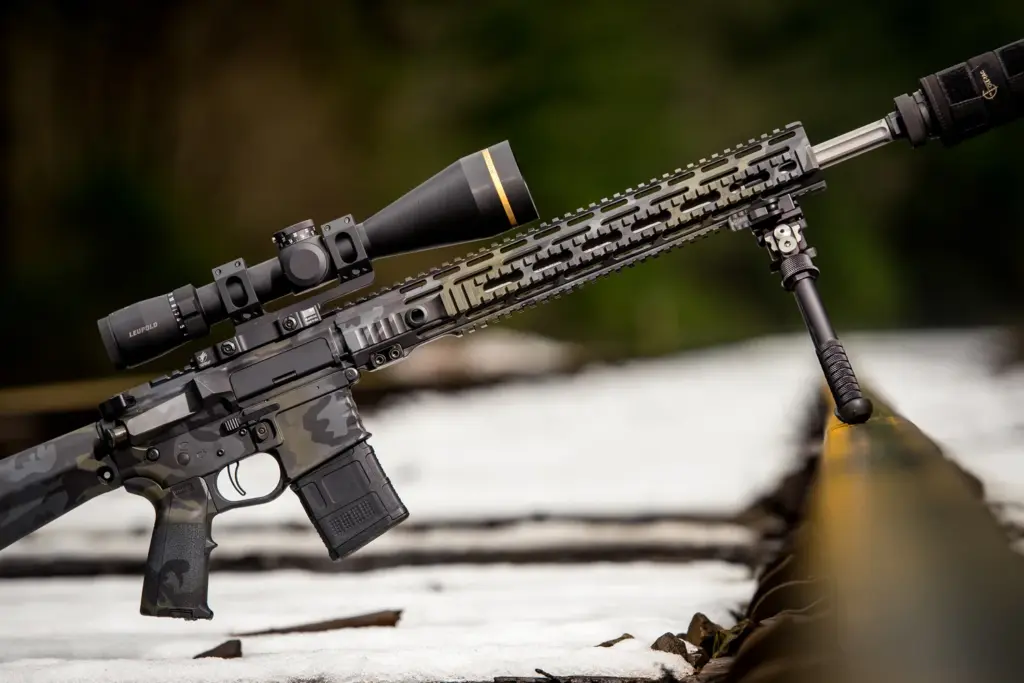 Multicam-black AR rifle on the Atlas PSR BT46-LW17 bipod over snowy railroad ties