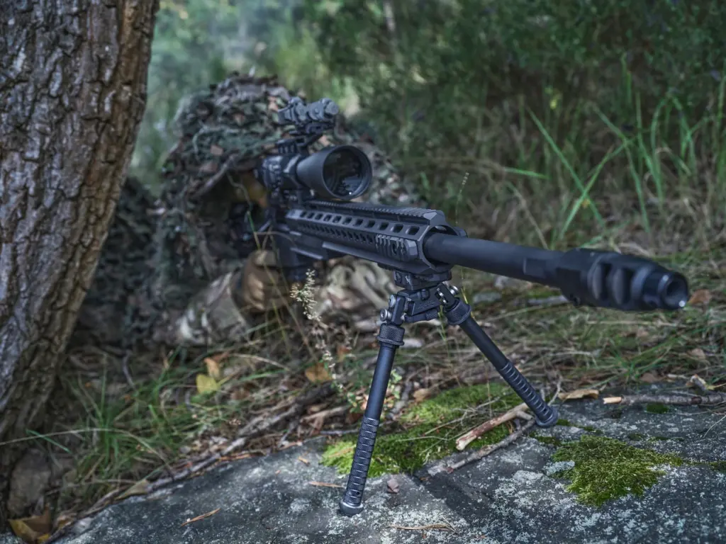 Ghillie-concealed sniper behind a black rifle supported by the tall Atlas PSR BT47-LW17 bipod