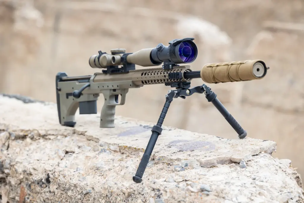 FDE precision rifle with suppressor on the Atlas Super CAL BT72-LW17 bipod against desert rubble